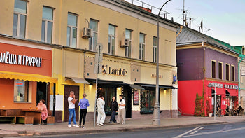People stand on a sidewalk in front of shops.